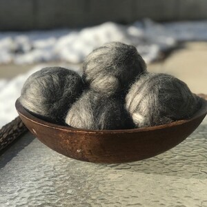 May include: Four gray wool balls in a wooden bowl. The balls are soft and fluffy, and they are perfect for adding a touch of texture to your home decor.