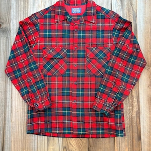 Puede incluir: Camisa de franela a cuadros rojos, verdes y amarillos con dos bolsillos en el pecho y cierre de botones. La camisa de manga larga tiene un cuello clásico.