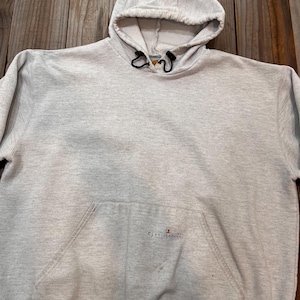 Pu&ograve; includere: Una felpa con cappuccio grigia Champion con un cordoncino nero e un piccolo logo Champion sulla tasca anteriore.