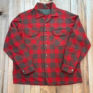 Op de afbeelding: Een rood en grijs geruit overhemd met twee borstzakken. Het overhemd heeft een kraag en manchetten met knopen. Het overhemd is gemaakt van een dik, warm materiaal, ideaal voor koeler weer.