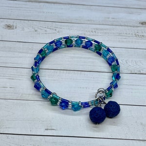 Può includere: Un braccialetto di perline blu e verdi con due ciondoli in pietra lavica blu scuro.