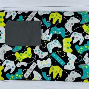 May include: Black fabric with a gray pocket and a repeating pattern of white, green, and yellow video game controllers.
