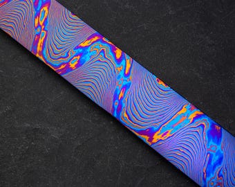 May include: A close-up of a blue, purple, and orange patterned metal surface. The surface has a wavy, abstract design.