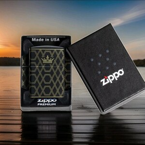 Puede incluir: Encendedor Zippo negro con un patr&oacute;n geom&eacute;trico dorado y dise&ntilde;o de corona, exhibido en su caja negra original. La caja est&aacute; abierta, revelando el encendedor y las palabras "Made in USA". El logotipo de Zippo es visible en la caja.