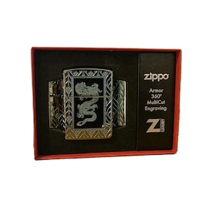 K&ouml;nnte beinhalten: Ein silberfarbenes Zippo-Feuerzeug mit Drachengravur, pr&auml;sentiert in einer schwarzen Box mit rotem Rand. Das Feuerzeug hat aufwendige Details und das Zippo-Logo, zusammen mit dem Text "Armor 360&deg; MultiCut Engraving".