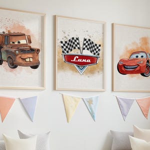 Peut inclure: Trois impressions d'art encadr&eacute;es repr&eacute;sentant des voitures de dessins anim&eacute;s. L'une montre une d&eacute;panneuse rouill&eacute;e, une autre un embl&egrave;me de course avec "Luna", et la troisi&egrave;me une voiture de course rouge. Des guirlandes d&eacute;coratives sont suspendues en dessous.