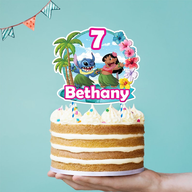 Puede incluir: Un pastel en capas con glaseado blanco y dos velas. El pastel est&aacute; cubierto con un adorno colorido con los personajes Stitch y Lilo, el n&uacute;mero 7 y el nombre "Bethany". El fondo es azul claro.