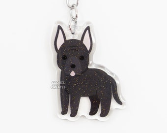 Puede incluir: Llavero de perro de dibujos animados en blanco y negro con detalles de purpurina. El llavero está unido a un anillo y una cadena de metal plateado.