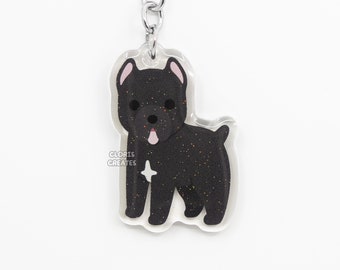 Puede incluir: Llavero de perro negro con purpurina y un anillo de llave plateado. El perro está de pie y tiene la lengua rosa fuera. El llavero tiene el texto "CLORIS CREATES".