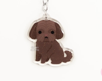 May include: A brown glitter shih tzu dog keychain with a silver key ring. The keychain is made of clear acrylic and has a sparkly finish.