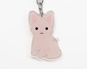 Puede incluir: Un llavero de gato rosa con purpurina y un anillo de llave plateado. El gato está sentado con las orejas levantadas y tiene una pequeña nariz y ojos negros. El llavero tiene el texto "CLORIS CREATES" impreso en la parte inferior.