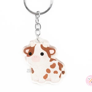 Llavero de vaca lechera marrón y blanca con forma de animal de granja / Dije acrílico con purpurina de arte chibi de dibujos animados / Regalo kawaii para amantes de los animales / Año de la vaca