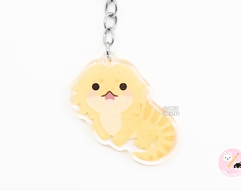 May include: A yellow bearded dragon keychain with a cute cartoon face. The keychain is made of clear acrylic and has a silver metal chain and ring.
