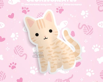 May include: A sticker featuring a cartoon illustration of a light orange tabby cat with white paws and a white chest. The cat is sitting with its tail curled around its body. The background is a pink pattern with white paw prints, hearts, and yarn balls.