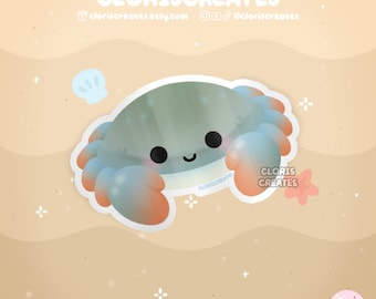 May include: A cute cartoon crab with a blue, green and orange shell on a sandy beach background. The crab has a happy expression and is surrounded by small white flowers.