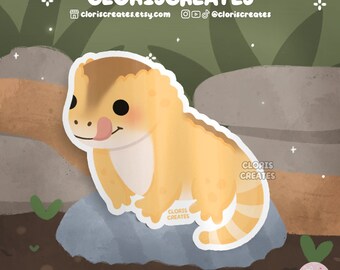 May include: A cartoon illustration of a yellow and orange gecko with a pink tongue sticking out, sitting on a gray rock. The gecko has a white stripe down its back and a white tail with orange stripes. The background is a green and brown forest.