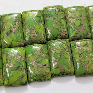 Puede incluir: Doce cabujones rectangulares de turquesa pulida, de color verde y dorado. Las piedras tienen un patrón de mármol con motas doradas.