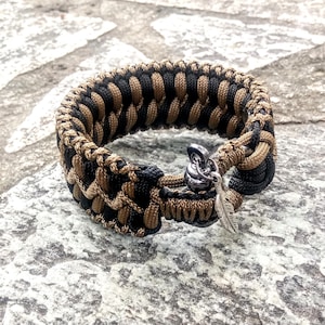 Pulsera de paracord, color negro, marrón dorado y microcordón marrón coyote. Grillete de metal.