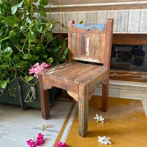 Puede incluir: Una silla de madera r&uacute;stica con un acabado desgastado. La silla tiene un dise&ntilde;o sencillo con un asiento rectangular y un respaldo con listones verticales. La silla est&aacute; hecha de madera recuperada y tiene un aspecto natural y desgastado.