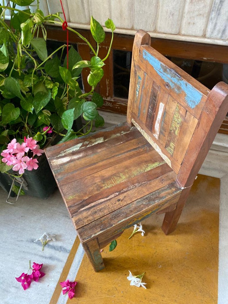 Puede incluir: Una silla de madera r&uacute;stica con un acabado desgastado. La silla es de color marr&oacute;n claro con acentos azules, verdes y amarillos. La silla est&aacute; hecha de madera recuperada y tiene un aspecto &uacute;nico y artesanal.