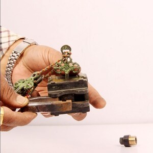 May include: A close-up of a vintage brass lock with a key and a small metal piece. The lock is green and has the number "46" on it. The lock is being held by a hand.