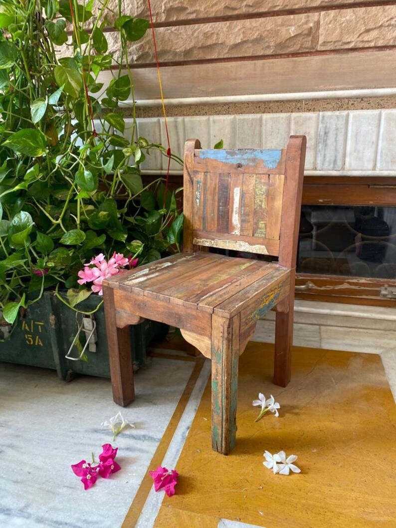 Puede incluir: Una silla de madera r&uacute;stica con un acabado desgastado. La silla tiene un dise&ntilde;o sencillo con un asiento rectangular y un respaldo con listones verticales. La silla est&aacute; hecha de madera recuperada y tiene un aspecto natural y desgastado.