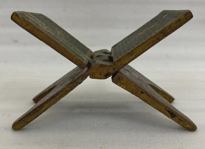 Puede incluir: Un atril de madera con forma de cruz. El soporte est&aacute; hecho de madera envejecida con un tono marr&oacute;n dorado y detalles en verde oscuro. El soporte est&aacute; dise&ntilde;ado para sostener un libro abierto para leer.