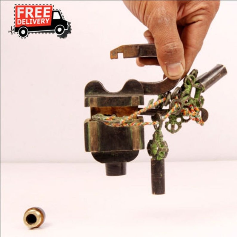 May include: Antique brass lock with an intricate design, featuring a keyhole, a chain, and a small metal ball. The lock is open and the keyhole is visible.