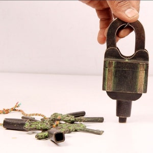 May include: A vintage brass padlock with a green patina and a set of five ornate keys. The keys are attached to a colourful string.