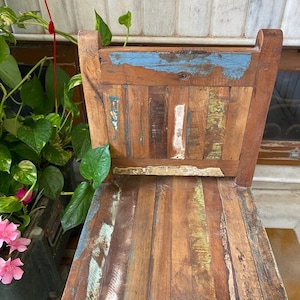 Puede incluir: Una silla de madera con un acabado desgastado. La silla est&aacute; hecha de madera recuperada y tiene un aspecto &uacute;nico y r&uacute;stico. La silla est&aacute; pintada en tonos de azul, verde y marr&oacute;n.