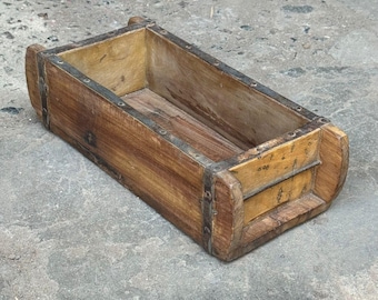 May include: A rectangular wooden box with rounded ends and metal banding. The box has a natural wood finish with visible grain and is empty. The box is likely an antique or vintage item.