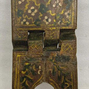 Puede incluir: Un peque&ntilde;o atril de madera con bisagras y acabado envejecido. El atril est&aacute; pintado con motivos florales y de vid en amarillo, verde y blanco sobre un fondo marr&oacute;n. Dise&ntilde;ado para sostener un libro en posici&oacute;n vertical.