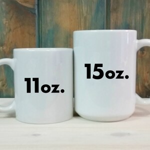 May include: Two white ceramic mugs with black text. The smaller mug is 11 oz and the larger mug is 15 oz.
