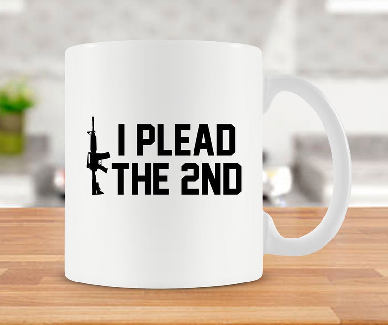 May include: White ceramic coffee mug with a black silhouette of a rifle and the text "I PLEAD THE 2ND".