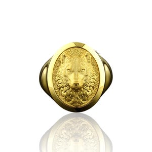May include: A gold ring with an oval-shaped wolf head design.