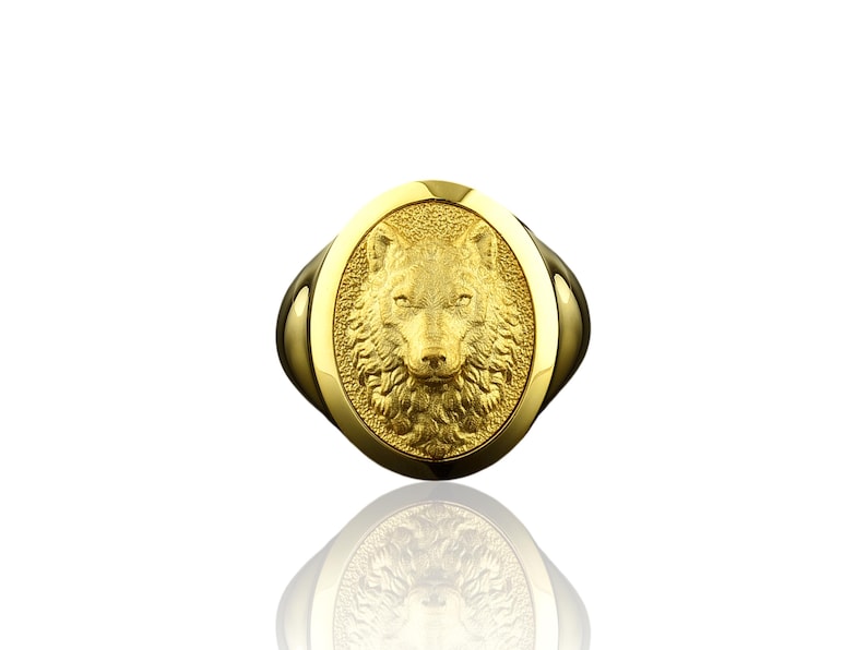 May include: A gold ring with an oval-shaped wolf head design.