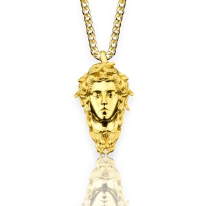May include: A gold chain necklace with a pendant featuring a detailed, three-dimensional depiction of Medusa's face.