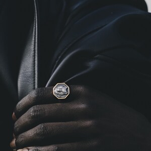 May include: A gold ring with a black and white octagonal stone featuring a wolf design.