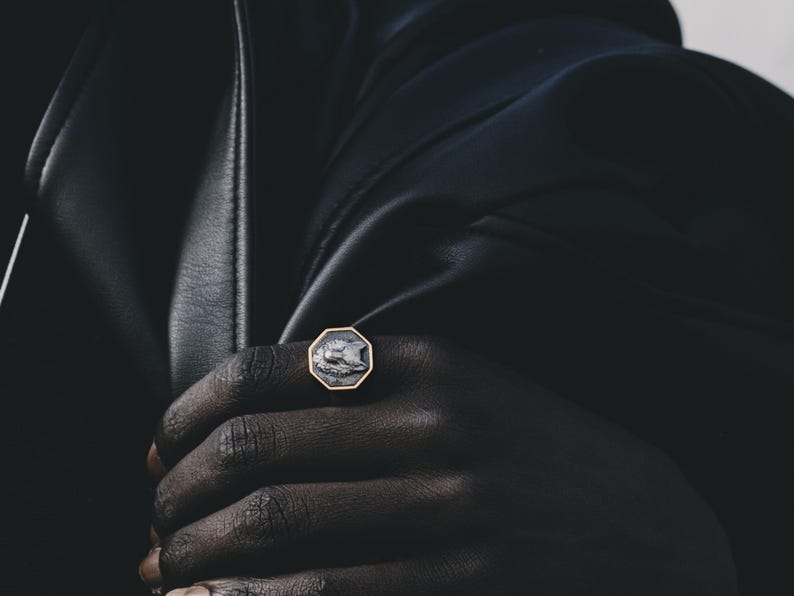 May include: A gold ring with a black and white octagonal stone featuring a wolf design.