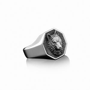 May include: A silver ring with an octagonal face featuring a detailed wolf head design.