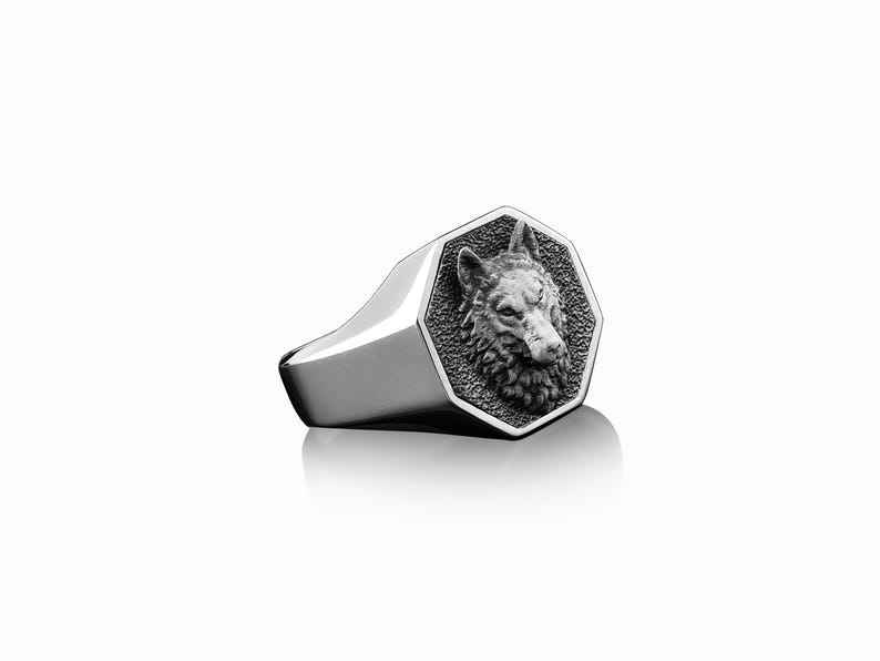 May include: A silver ring with an octagonal face featuring a detailed wolf head design.