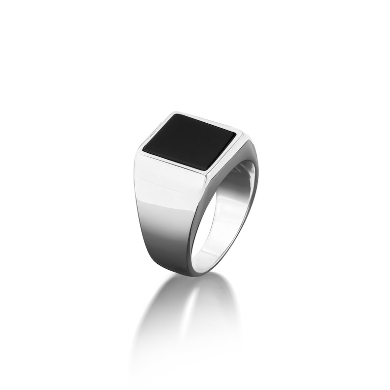 May include: A silver signet ring with a black square gemstone.
