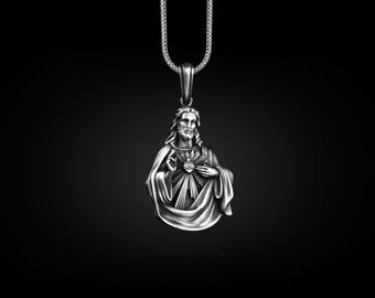 May include: Silver pendant necklace featuring a detailed depiction of Jesus Christ with his heart exposed and a crown of thorns. The pendant is on a silver chain.