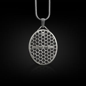 May include: Silver pendant necklace with a round, textured design. The pendant has the words "Text me" engraved on it.