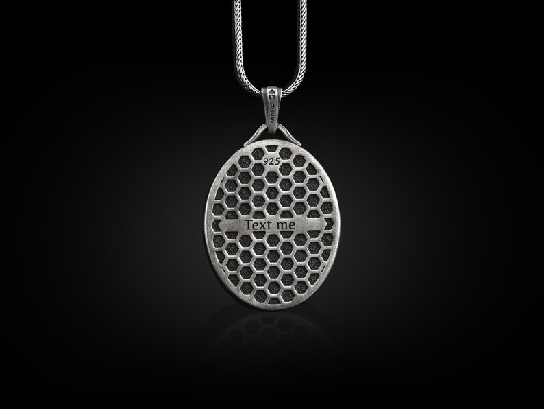 May include: Silver pendant necklace with a round, textured design. The pendant has the words "Text me" engraved on it.