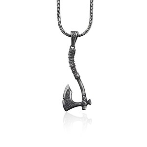 May include: A silver necklace with a pendant shaped like an axe. The axe has a detailed design and a textured handle.
