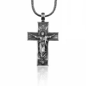 May include: Silver pendant necklace featuring a detailed cross with a depiction of Jesus Christ. The cross has a raised design and a textured finish.