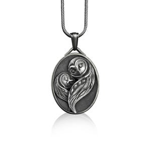 May include: A silver pendant necklace featuring two owls in a heart shape. The owls are intricately detailed and have a realistic appearance.