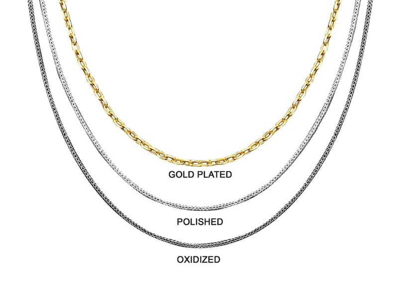 May include: Three silver chains, one gold plated, one polished, and one oxidized. The chains are layered on top of each other.