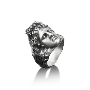 Peut inclure: Une bague en argent avec un visage sculpt&eacute; d&eacute;taill&eacute; d'une personne avec une couronne de feuilles.